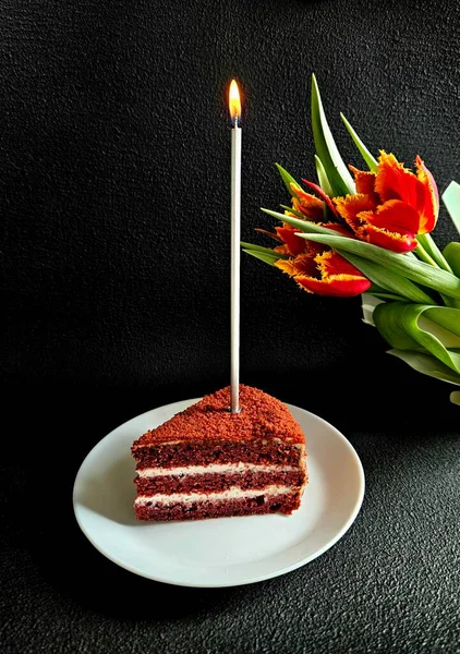 birthday cake on a black background. the concept of birthday, a cake and a birthday card. piece of birthday  cake with candles with beautiful flowers on the background.