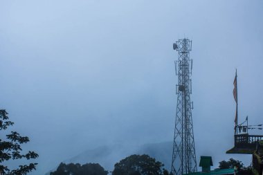 Telekomünikasyon kulesi, kırsal bölgelerdeki bağlantıyı sembolize eden sisli dağlık bir bölgede ortaya çıkıyor..