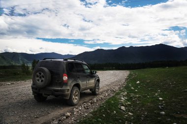 Offroad araba konsepti ile dağlar. Ön planda, çakıl taş yolun üzerinde Suv.
