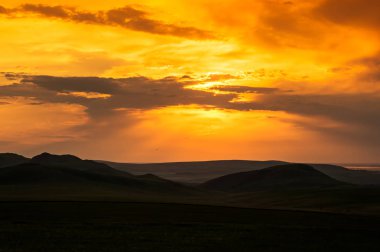 Tepeler ve parlak gökyüzü gün batımı sırasında. Doğanın kompozisyon. Bulutların üzerinde bir turuncu sky arkasında parlak turuncu ve sarı güneş ışınlarının kızdırma. tepeler üzerinde