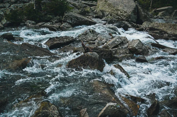 Stone texture of the river. Strong current of a mountain river in the background. Tinted instagram photos