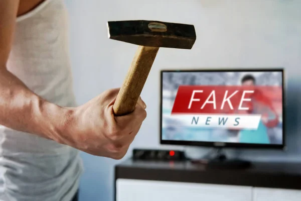 man wants to break the TV. guy swung a hammer at the screen. . Fake news on the TV screen, HOAX concept. News report with false news. Truth misrepresented in the news on a modern TV. nutcase, nutter