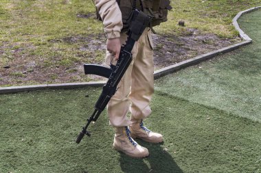 Müslüman militan tüfekle. bir Kalaşnikof çim arka planı tutarak hafif askeri üniformalı bir asker