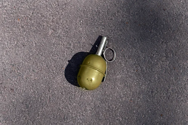 green grenade resting on a battlefield. Hand grenade RGD-5 on asphalt. Lost green garnet. real weapons are dangerous, fragmentation grenade.