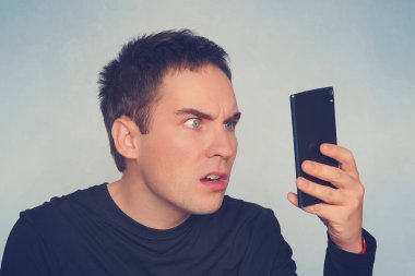 Tiksinti adam kısa mesaj okuma. adam sürpriz içinde belgili tanımlık smartphone perde inceliyor. Merak ediyorum duygu. öfke ve kızgınlık. Yavaş bir Internet bağlantısı. bağlantı kesildiğinde.