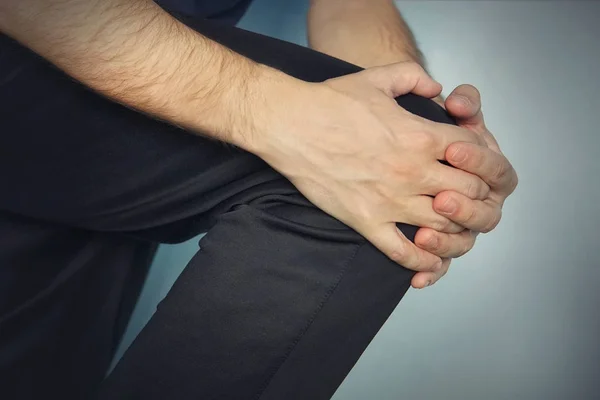 Der Junge Mann Hält Seine Hände Über Seinem Kranken Knie — Stockfoto