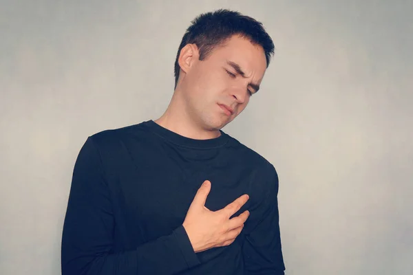 man suffering from chest pain, having heart attack or painful cramps, pressing on chest with painful expression.
