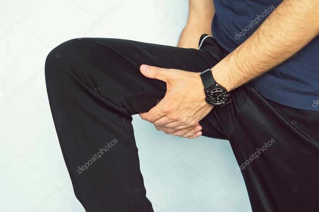 Muscle injury. Man with sprain thigh muscles. Athlete in sports shorts clutching his thigh muscles after pulling or straining them while jogging