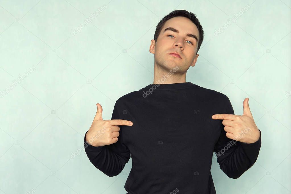 man pointing at his t-shirt can be used as a clothes design template on a blue background. T-shirt with long sleeves black. mocap for design