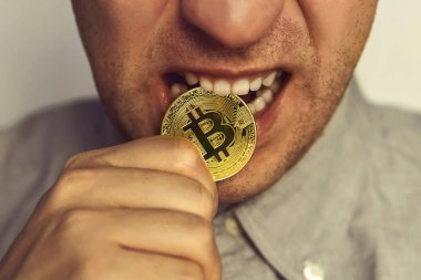 Bitcoin. Adam altın sikke dişleriyle ısırır.