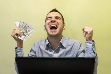 genç modern işadamı onun dizüstü bilgisayarınızla çalışırken onun başarı ile heyecanlı. Para tutan için sevinç, bağıran adam. 500 dolar elinde. Piyango kazanma