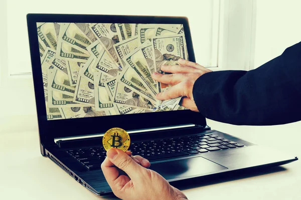 Making money trading bitcoins. Big profits from mining of cryptocurrencies. Laptop with money and bitcoin in the hands of a businessman. e-Commerce. selling bitcoins. The growth rate of bitcoin