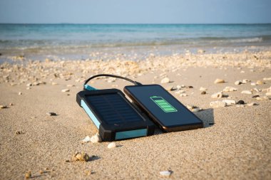 çerçevesiz Smartphone yakın kopya alanı, güç ve enerji geri yükleme kavramı ile kumlu bir plaj üzerinde. su geçirmez, geçirimsiz