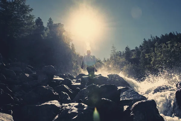 Een Man Staat Een Steen Tegen Een Waterval Onder Stralende — Stockfoto