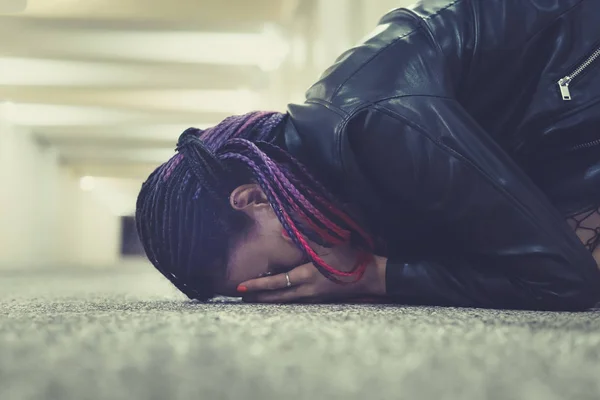 Chica triste y solitaria llorando con una mano cubriéndose la cara. Mujer joven sentada en el suelo en el paso subterráneo y llorando pesadamente de dolor — Foto de Stock