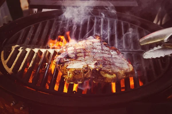 Barbecue chicken cooking on an outdoor grill. A piece of pork steak on an open fire