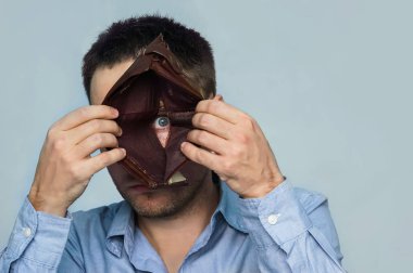 Genç işadamı parayı kaybettim. Negatif duygular ve hayal kırıklığı, hayal kırıklığı ve üzüntü göstererek bir boş deri cüzdan dibinde bir delikten bir adam görünüyor