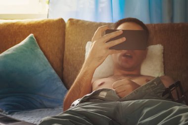 Genç çıplak adam porno izliyor. bir akıllı telefon ekranı izlerken kanepede genç adam otuzbir