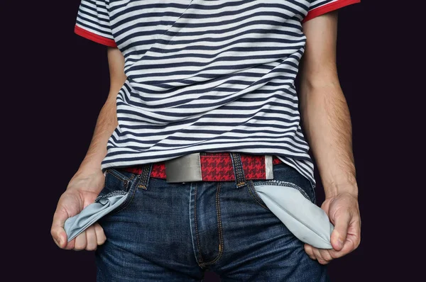 Poor man in jeans with empty pocket isolated on black. The guy holds hands empty pockets jeans. Guy demonstrates his poverty failure and absence of money and Finance