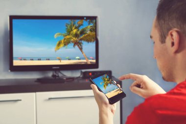 Smartphone ile olgun adam evde film izlerken bir TV'ye bağlı. Ağ tv ve öngören fotoğraflarda smartphone ile rahat adam bağlı