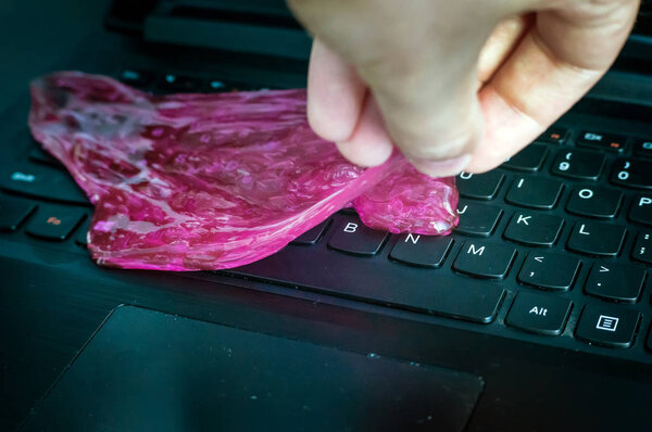 Red soft gel cleaning dust in hand. Cleaning your computer's keyboard.