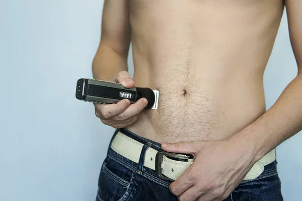 Closeup of a young man trimming the hair of his pubis with an electric trimmer. concept of a clean healthy body for men. Man haircut pubic hair with a clipper — Stock Image Closeup Young Man Trimming Hair His Pubis Electric Trimmer Concept Stock Picture