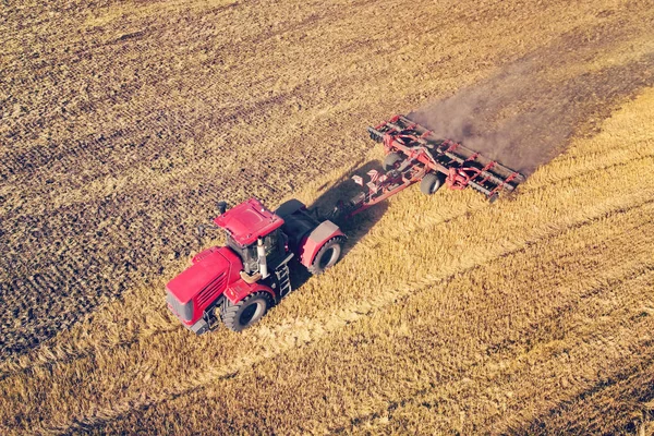 Z lotu ptaka dron pola żniw z ciągnikiem kosi suchą trawę. Jesienne żółte pole ze stogiem siana po żniwach widok z góry. Zbiory na polach. Zapasy siana na zimę. Widok z góry. — Zdjęcie stockowe