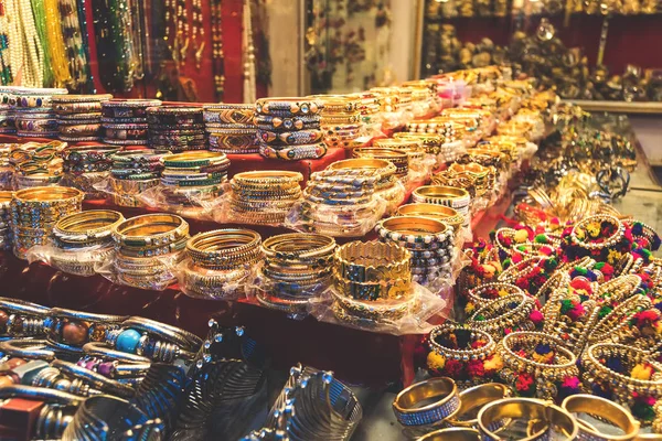 Traditional indian bangles and bracelets at the street market in Udaipur, Rajasthan, India. Jewelry made of gold-plated metal with multicolored stones in the Asian style. Tibetan bracelets