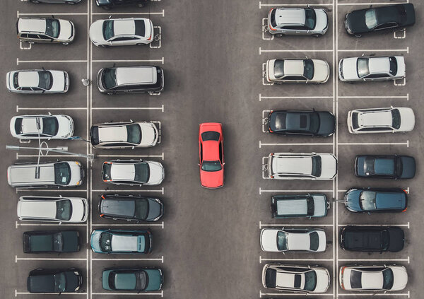 Top view of the crowded Parking lot with quadcopter or drone. Original bright automobile among the grey of mediocre cars. Parking space search, No parking space.