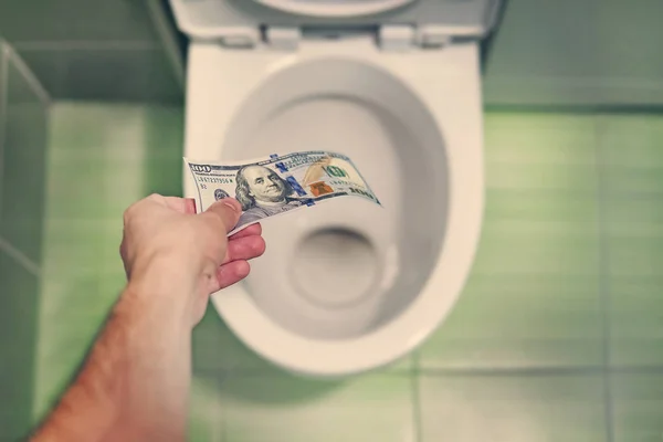 concept of senseless waste of money, loss, useless waste, large water costs, in the toilet wash a thousand dollars bill.