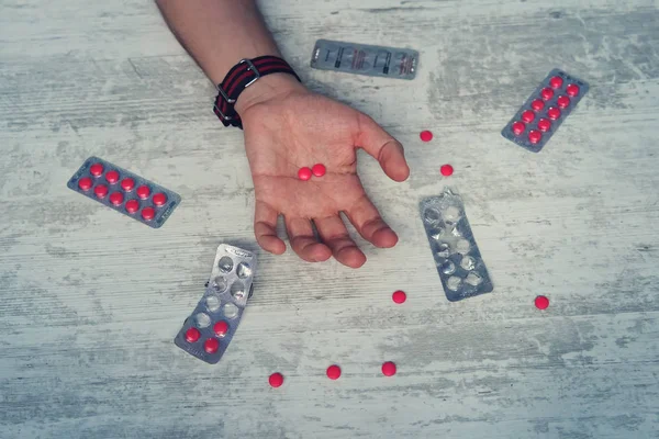 关闭过量的药片和上瘾的人的手 男子自杀的过量在药物 年轻男子手中的红药片 — 图库照片