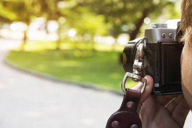 Profesyonel erkek fotoğrafçısı yakın çekim. Genç profesyonel Erkek kameraman yeşil Park modern kamera çekim açık alan bulanık. Fotoğrafçı alarak fotoğraf açık. Çekim işlemi
