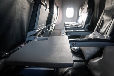 Uçak Koltuk tepsi açık boş yemek bekliyor. Bir Boeing kabin içinde. Ekonomi sınıfında koltuklar.