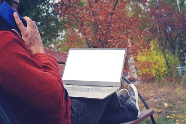 Homme travaillant à l'extérieur toujours connecté avec son smartphone et son ordinateur portable fidèle. jeune homme, pigiste travaillant en plein air à l'automne Park — Photo