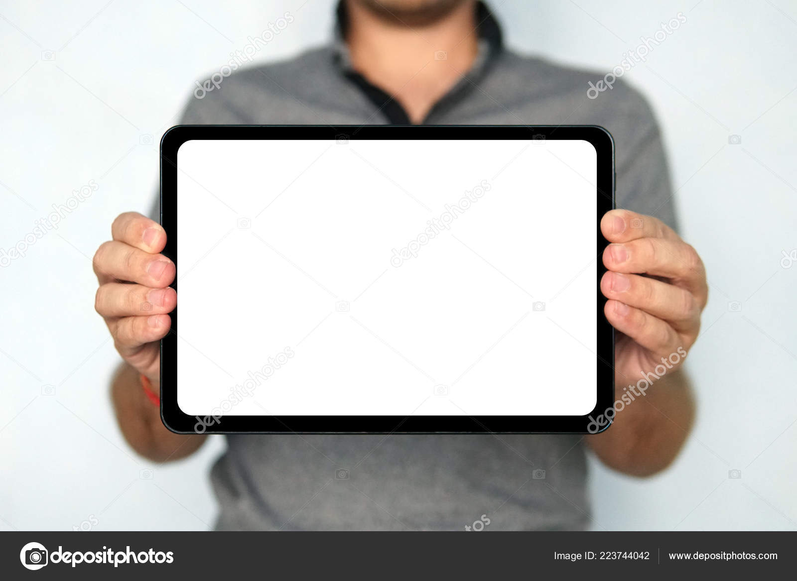 Jeune homme tient une tablette tactile sur fond blanc isolé. La tablette  numérique de grande taille
