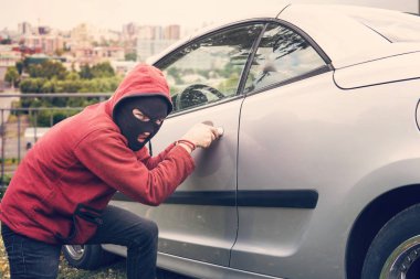 Maskeli adam ağız kavgası ve izleyiciye seyir birinin araba tatili. Hırsız hoodie ve gizli yüz picklock için gözlerini kameraya sabitleme Park edilmiş araç girişimi yapar. Kötülük-Fail hasar Araba kilidi.