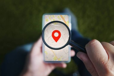 Büyüteç coğrafi konum ve smartphone ile online şehir içinden isteyen kırmızı simgeyle holding erkek eller görüntüsünü ekranda göster. Gezinti için mobil net kullanarak kavramı