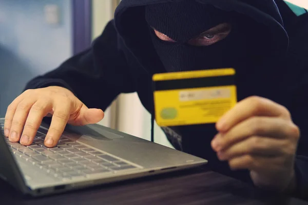 Man in Rover masker gebruikt internet, bankrekening en kredietfaciliteiten. Phishing-aanval door mannetje met verborgen gezicht. Hacker invoert gestolen financiële gegevens. Vertrouwelijke informatie werd genomen door de fraudeur — Stockfoto