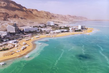 Mavi su ölü deniz, resort kasaba Ein Bokek İsrail çölün ortasında arka plan üzerinde ön planda. İnsanlar turist tuzlu suda yıkayın. Yararlı Spa tedavileri. öğleden sonra
