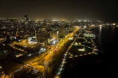 İsrail 'in Tel Aviv limanı yakınlarındaki kumsalda modern gökdelenler ve lüks otellerle Tel Aviv şehrinin gece hava manzarası.