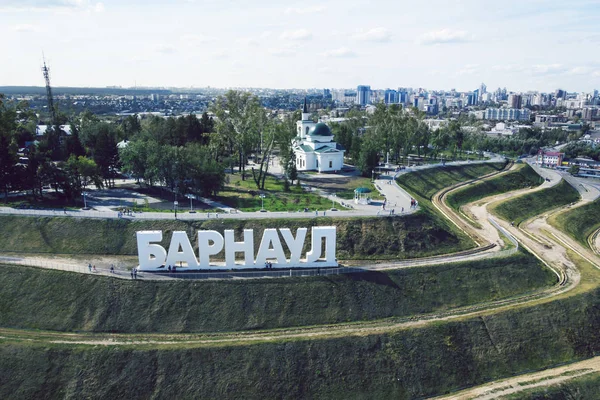 A picturesque bird\'s eye view to the letters on the slope spelling out a Russian city\'s name. The developed touristic area with the monumental city name construction on the stepwise green hill.