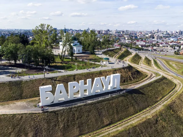 Magnificent view of capital letters on the stepped hill spelling out a Russian city's name. City's name constructed on the staged upland in recreatrion zone. Monumental letters on the city background.