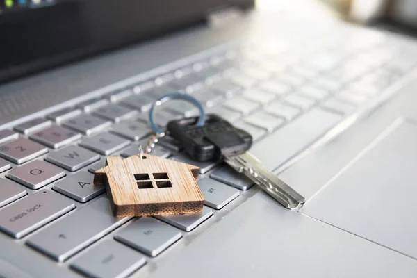 Mortgage concept with keys and house-shaped key ring on laptop keyboard. Find dream house in internet concept. Online assistance in searching dwelling. Close up of key lying on computer keyboard