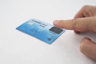 İzole edilmiş kredi kartı ve erkek parmağı biyometrik sensöre dokunuyor. Kredi kartından biyometrik doğrulama. Alıcı alıcı satın alırken parmağıyla sensörü kapatmış olmalı. Parmak izi tarayıcısı. Güvenli ödeme