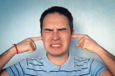 gürültü ve işitme kavramı - dinleme sorunları veya stres, kontrast etkileri reddedecek çığlıklar, kulakları tıkalı öfkeli genç adam. adam onun kulaklarını parmaklarıyla durdu.