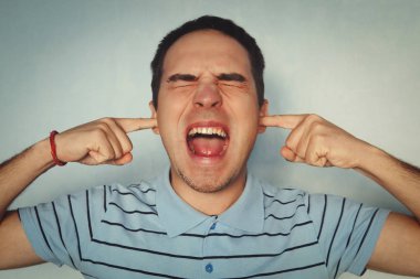 Stüdyo çekim rahatsız ve Kızıl saçlı beyaz adam duygu rahatsızlık işitme gürültü veya sakin, kulakları ile işaret parmakları kulak tıkacı gibi kapsayan, şaşı ve antipati dişler kenetlenmesi rahatsız