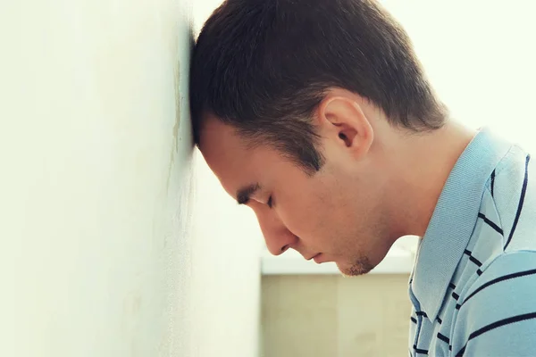 Deprimido hombre su cabeza contra una pared. tipos golpeando su cabeza contra la pared. chico aburrido en la depresión . — Foto de Stock