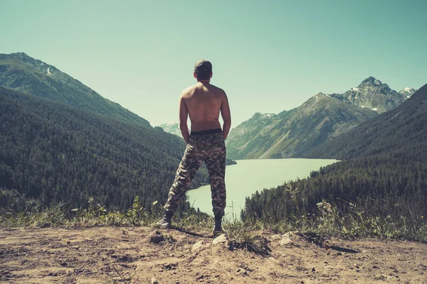 Mira sobre el lago de montaña Kucherlinskoe desde arriba, Altay, Rusia. Un hombre admira el paisaje montañoso en la cima de la montaña. Día de verano . — Foto de Stock