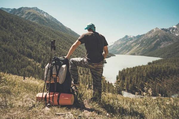 Hombre deportivo de pie con mochila en la cima de la montaña y hermosas montañas atbright día soleado. Paisaje con el hombre, rocas con picos nevados, glaciares, nubes en altay. Viajar. Trekking. Vintage. — Foto de Stock