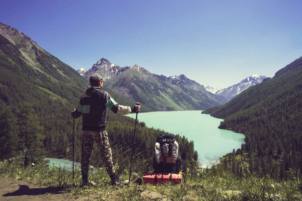 Foto de la espalda del turista con bastones con las manos en la colina cerca del lago. palos de retención turística para caminar nórdico . — Foto de Stock